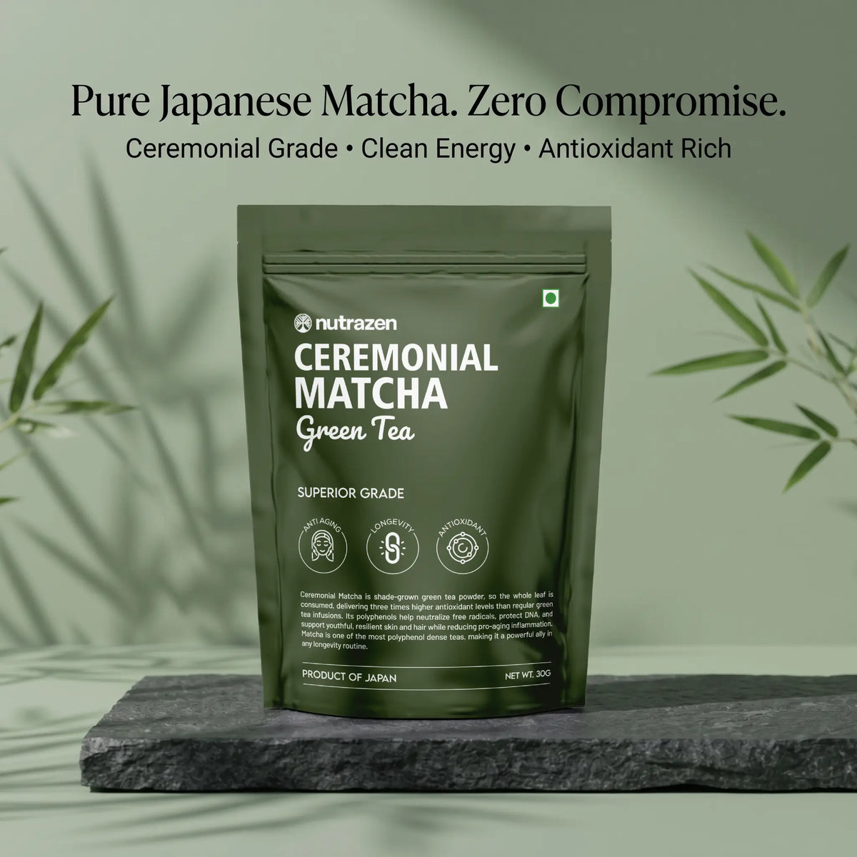 A dark olive green stand-up pouch of nutrazen Ceremonial Matcha Green Tea, displayed on a dark slate block with soft bamboo leaf shadows against a sage green background.