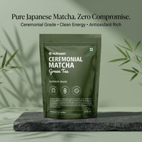 A dark olive green stand-up pouch of nutrazen Ceremonial Matcha Green Tea, displayed on a dark slate block with soft bamboo leaf shadows against a sage green background.