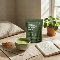 Ceremonial matcha green tea package on a table with a bowl of matcha and a notebook.